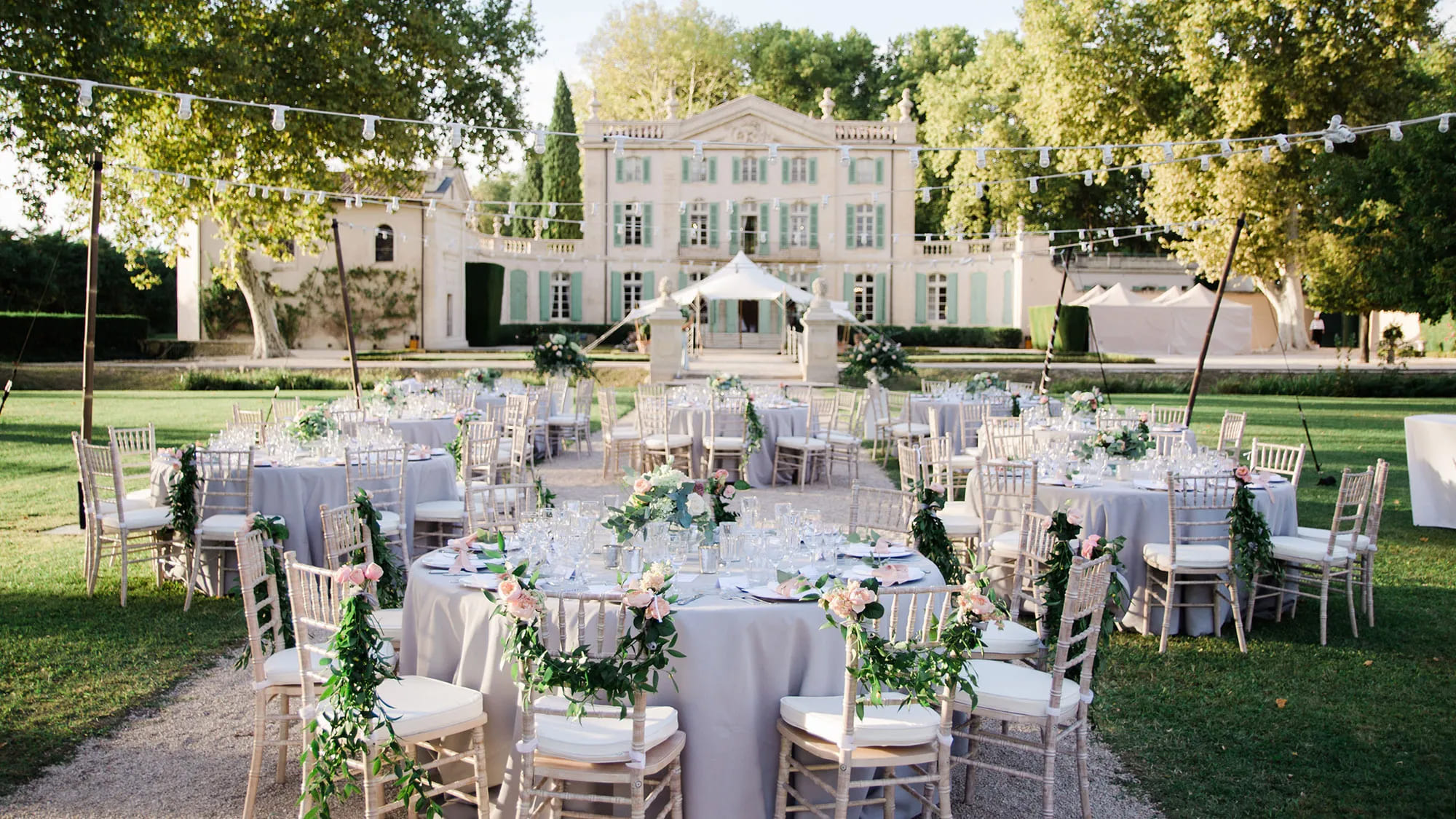 Réception en château avec tables blanches dans un jardin